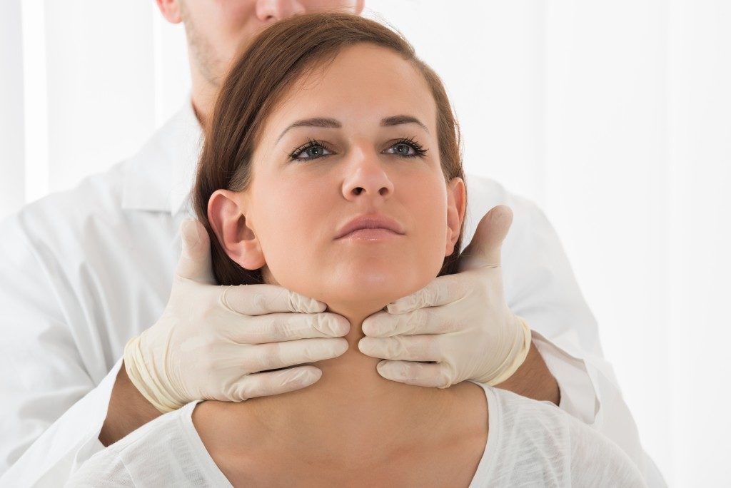 doctor checking throat of woman