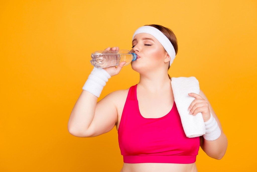 woman in working out clothes drinking water