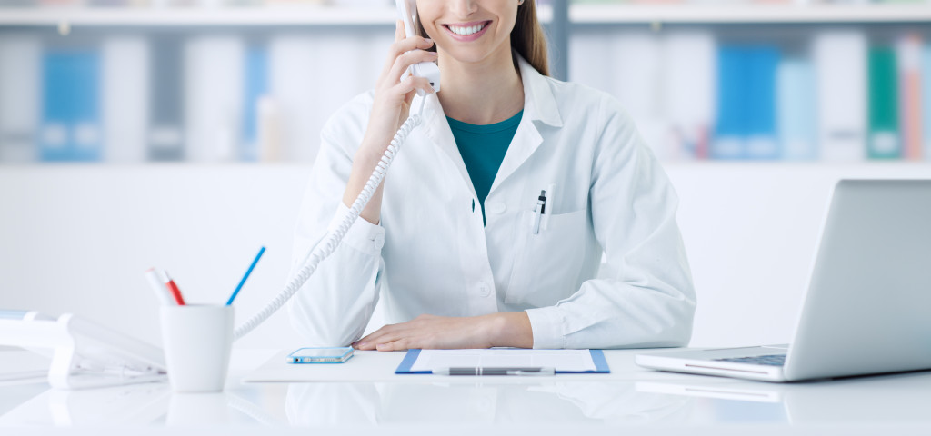 female doctor working at desk answering the phone